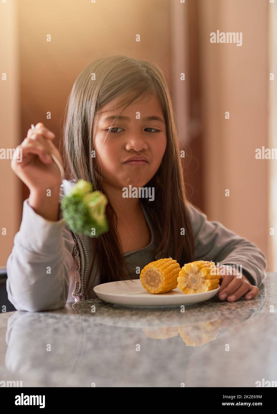 Warum werde ich wieder gefüttert. Kurzer Schuss eines kleinen Mädchens, das sich weigert, ihren Brokkoli zu essen. Stockfoto