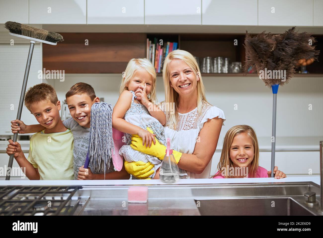 Mütter bekamen viele Helfer, um ihr Zuhause makellos sauber zu halten. Porträt einer Mutter und ihrer Kinder, die zu Hause gemeinsam arbeiten. Stockfoto