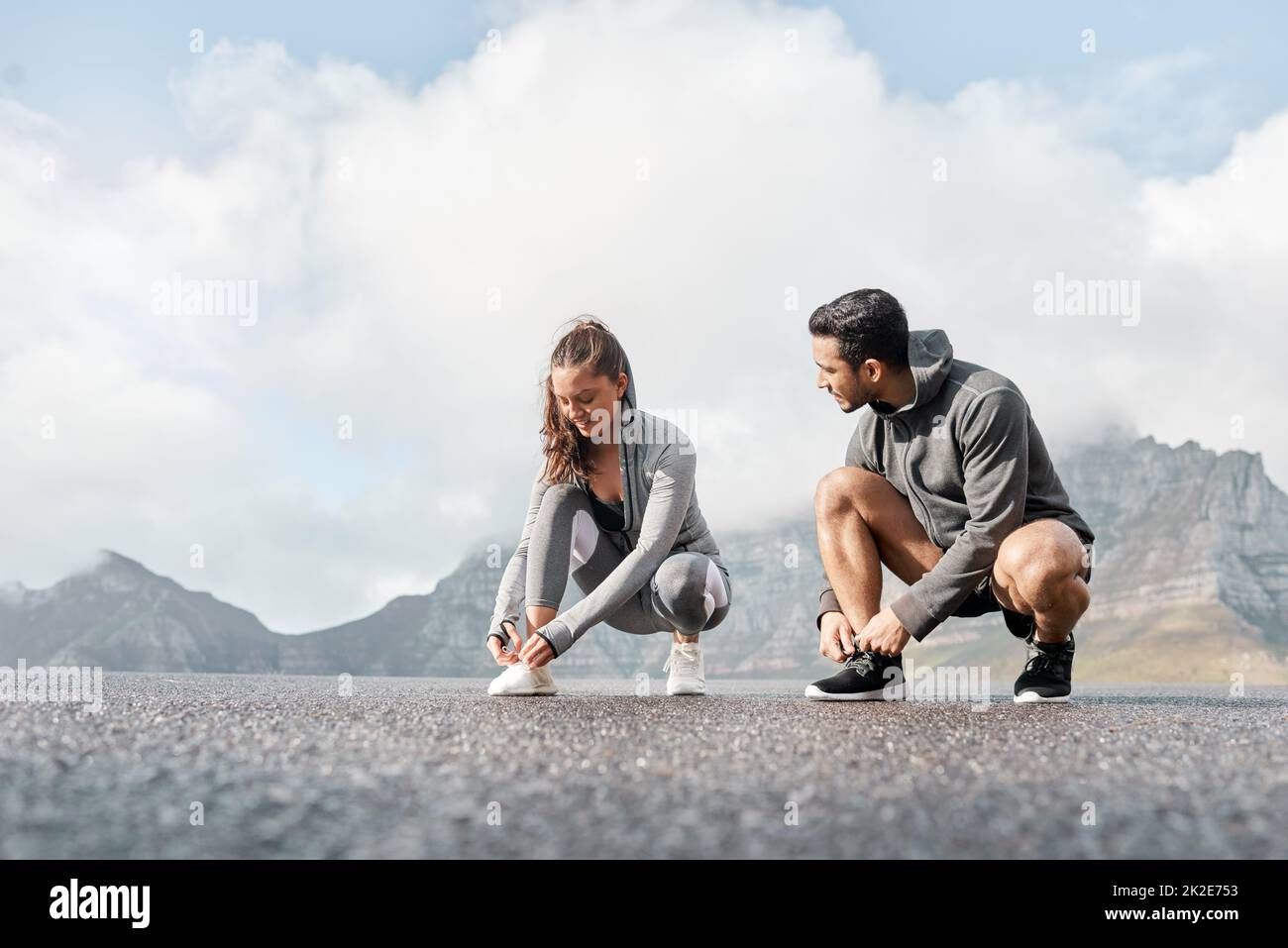 Unsere Laufschuhe haben Magie in sich. Aufnahme eines sportlichen jungen Mannes und einer jungen Frau, die beim Training im Freien ihre Schnürsenkel binden. Stockfoto