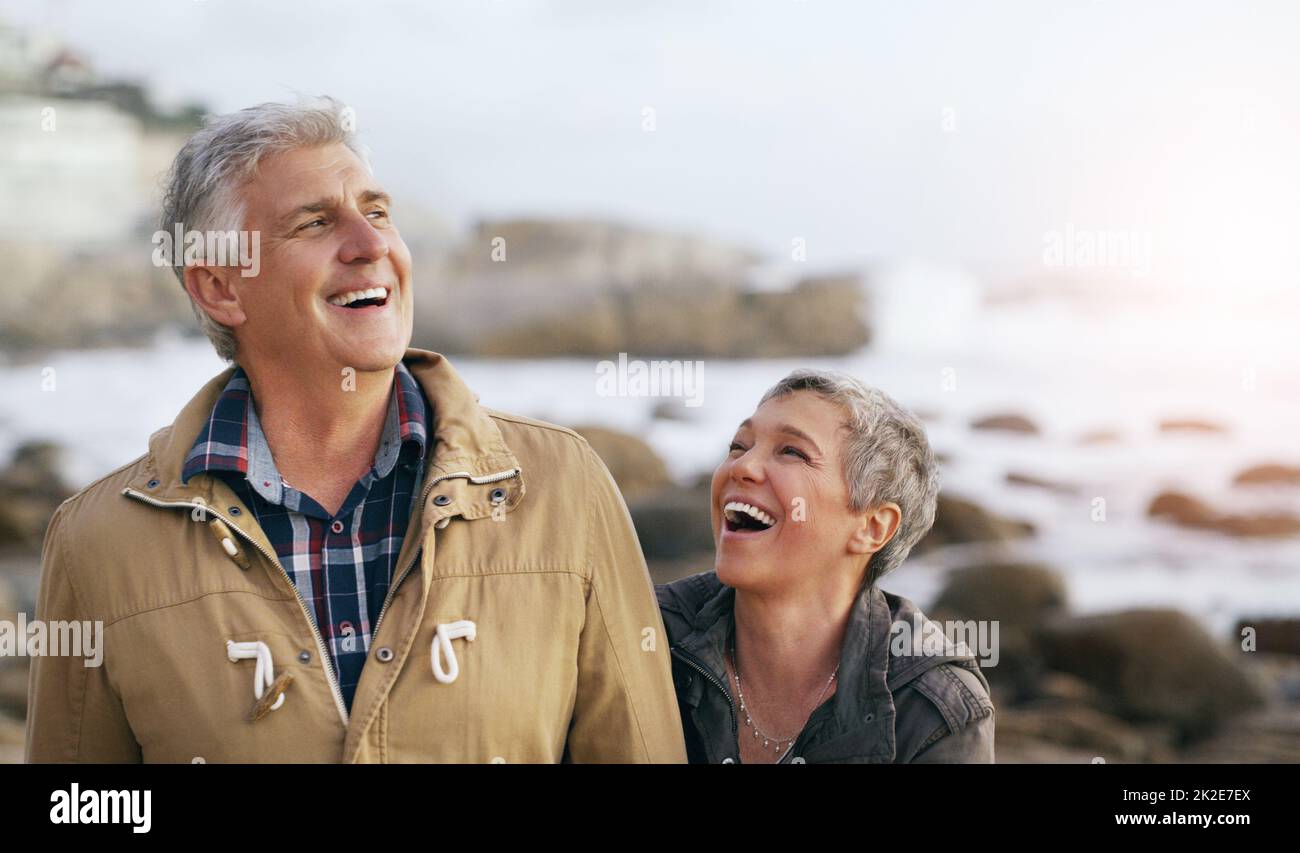 Wir haben immer die besten Lacher miteinander geteilt. Aufnahme eines wunderschönen älteren Paares, das einen Spaziergang am Strand gemacht hat. Stockfoto