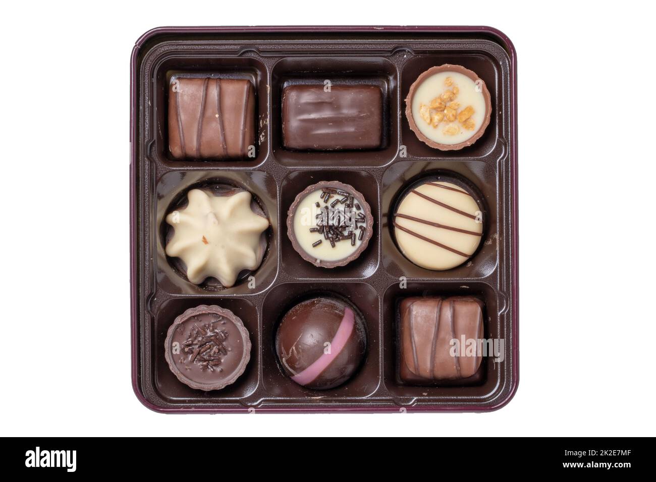 Nahaufnahme einer Schachtel mit feinen Schokoladenbonbons in einer wunderschönen Plastikbox isoliert auf weißem Hintergrund. Überraschungsgeschenk zum Valentinstag oder zu anderen festlichen Anlässen. Makro. Stockfoto