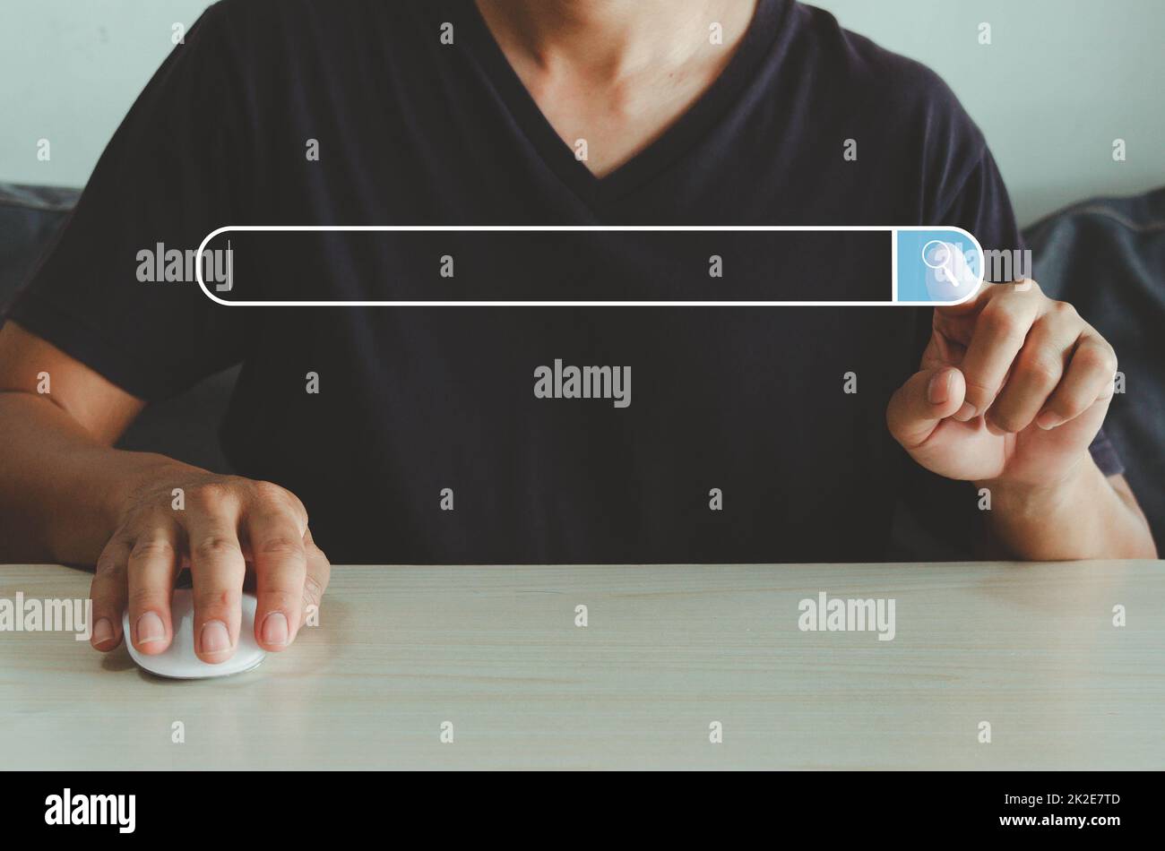Die Hand berührt das Symbol für die Suche auf dem virtuellen Bildschirm für die Web-Suchmaschine und hält die Maus auf der Tabelle. Stockfoto