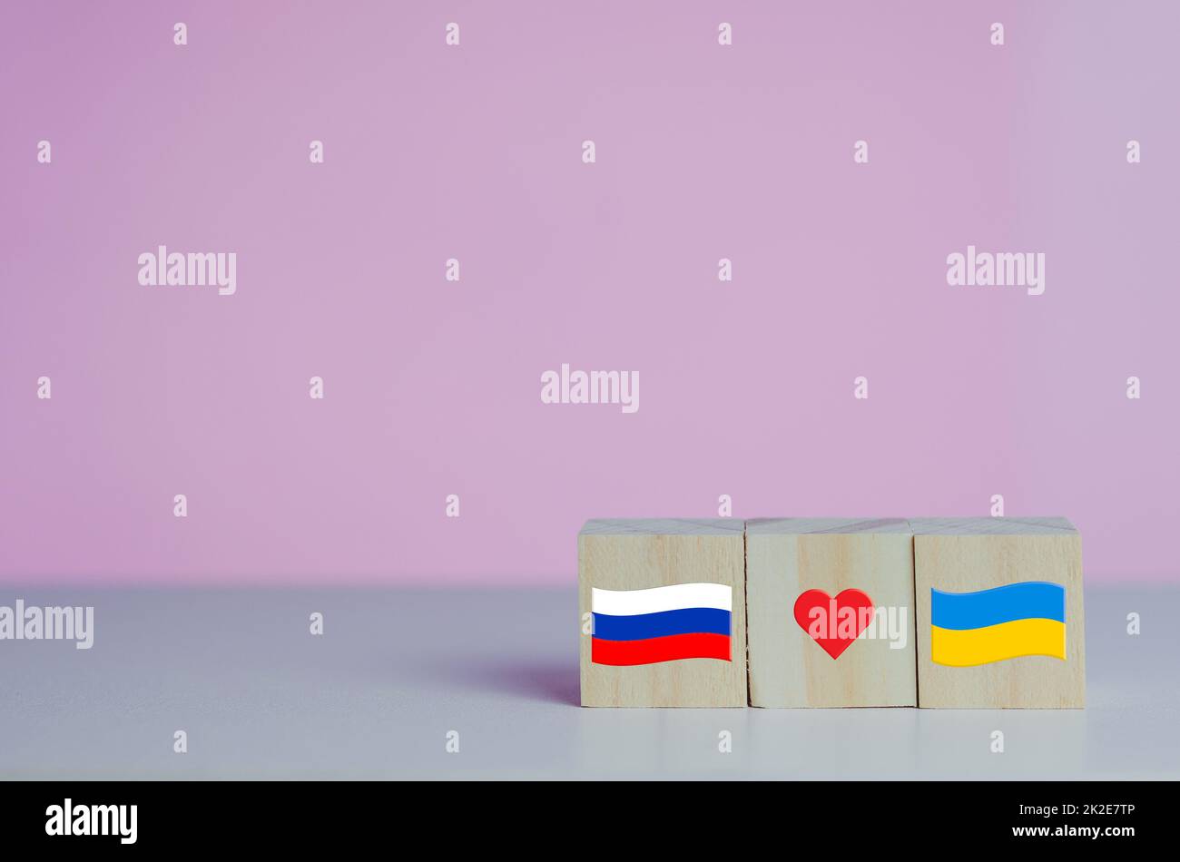 Holzwürfel mit russland-Flaggensymbol und ukraine-Flagge mit rotem Herzsymbol auf dem Hintergrund. Stockfoto
