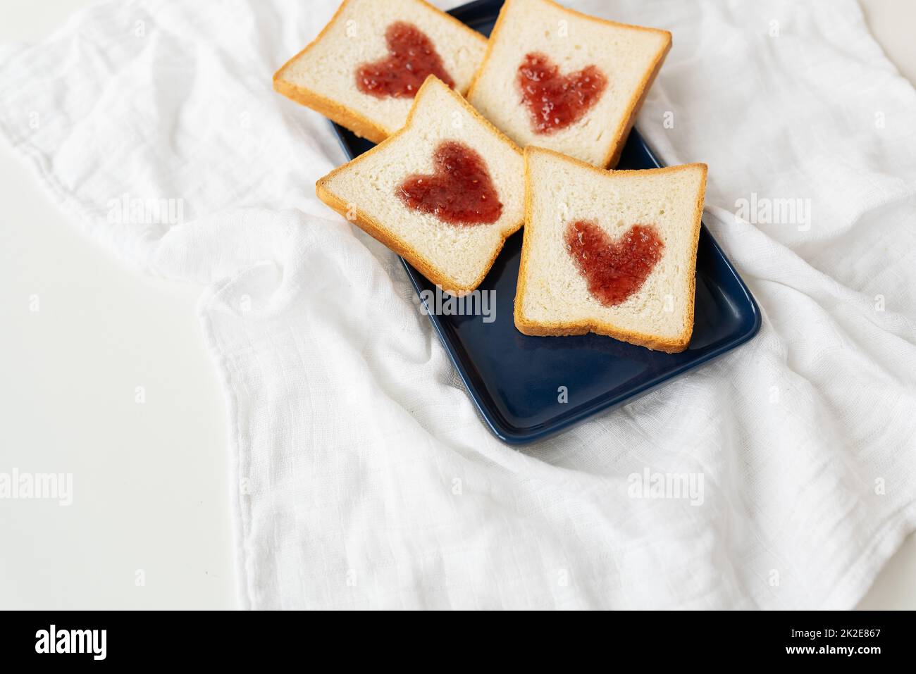 Toast, auf dem das Herz aus Marmelade besteht. Überraschendes Frühstückskonzept im Bett. Romantik für St. Valentinstag, ein Ort für eine Inschrift. Stockfoto