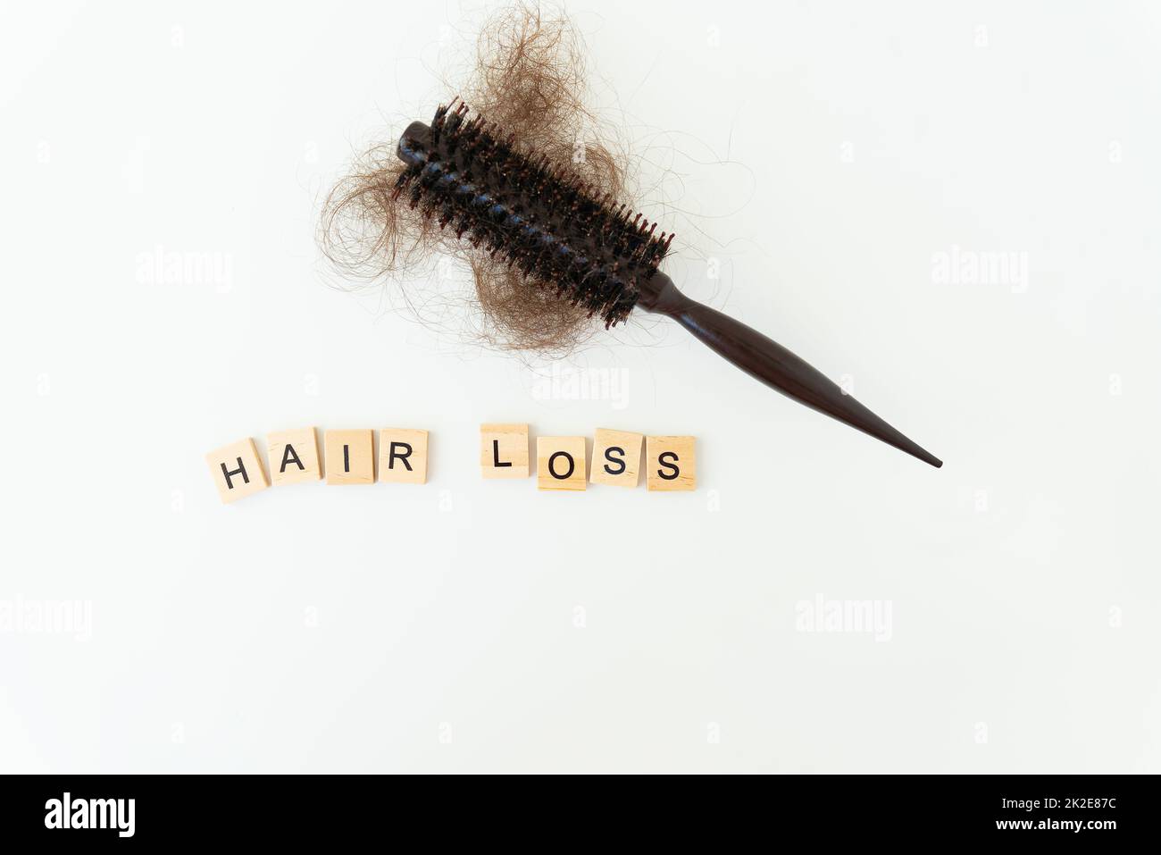 Haarausfall im Kamm, täglich schwerwiegendes Haarausfall-Problem, auf weißem Hintergrund. Inschrift in Holzbuchstaben. Stockfoto