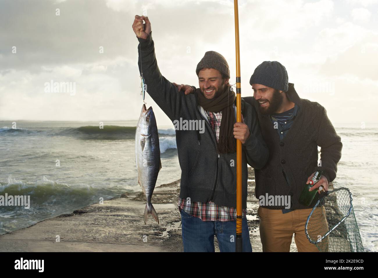 Erinnerungen, die ewig dauern werden. Aufnahme von zwei jungen Männern, die am Strand fischen. Stockfoto