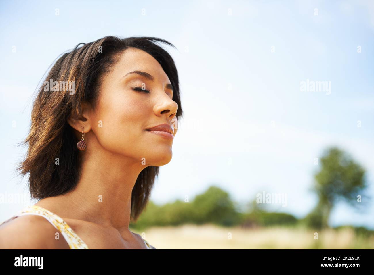 Die frische Luft einatmen. Eine hübsche Frau mit geschlossenen Augen im Freien. Stockfoto