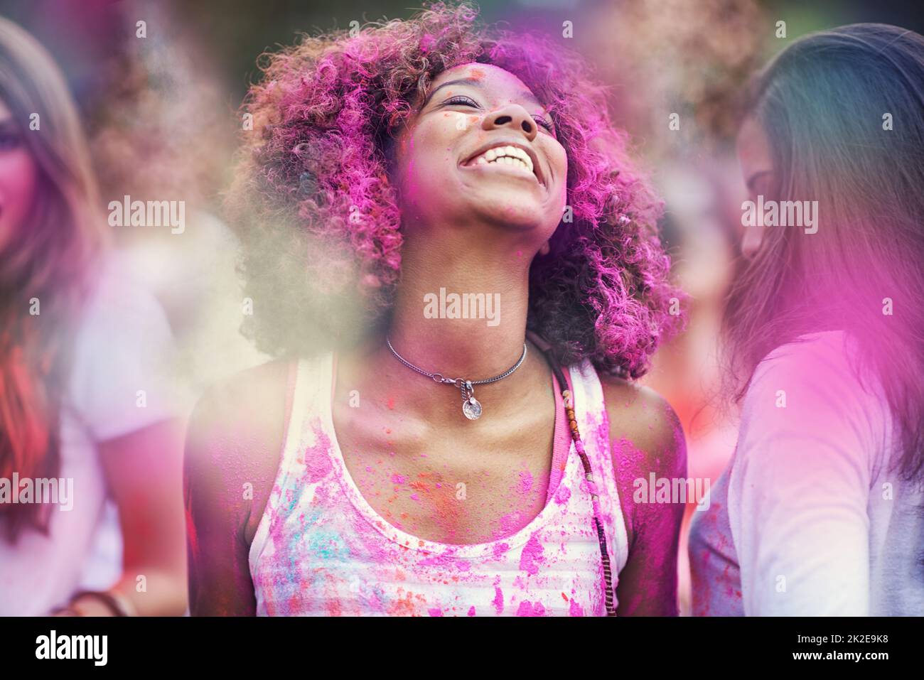 Jagd auf den Regenbogen. Aufnahme von glücklichen Freunden, die Spaß mit Pulverfarbe haben. Stockfoto