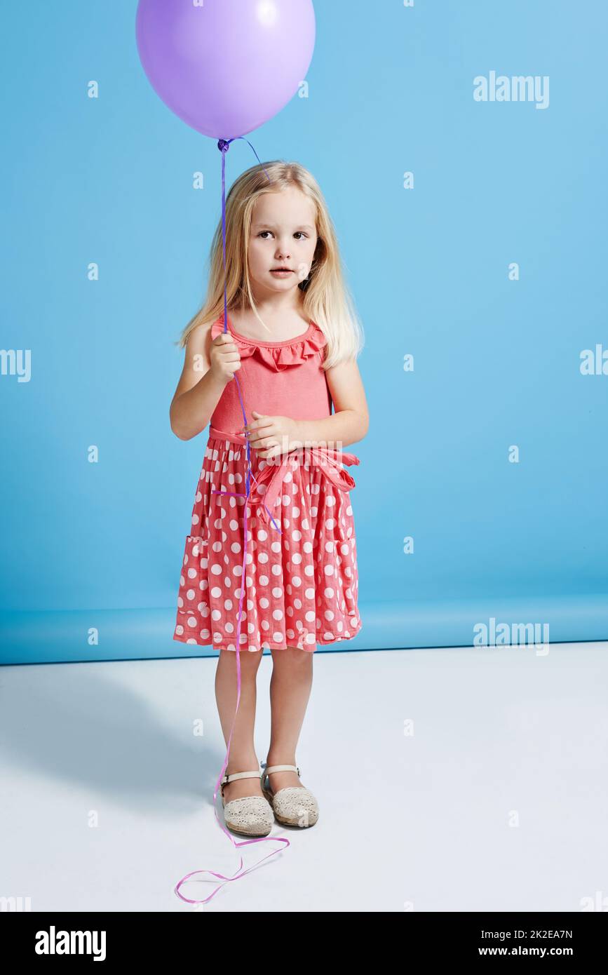 Bereit zum Abheben. Aufnahme eines niedlichen kleinen Mädchens, das einen Ballon auf einem blauen Hintergrund hält. Stockfoto