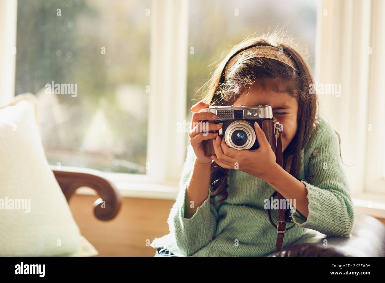 Wer weiß, wohin ihr Hobby sie führen könnte. Aufnahme eines kleinen Mädchens, das zu Hause mit einer Vintage-Kamera fotografiert. Stockfoto