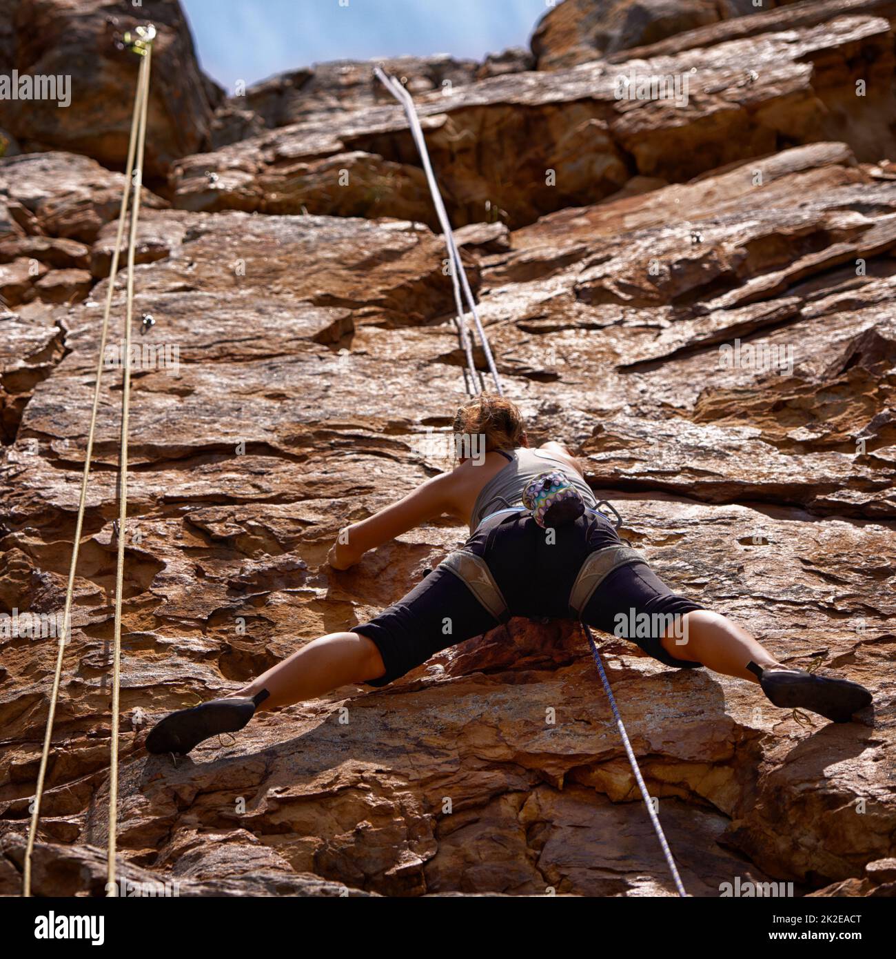 Shes fordert sich selbst auf diesem Aufstieg heraus. Aufnahme einer jungen Kletterin, die eine Felswand überquert. Stockfoto