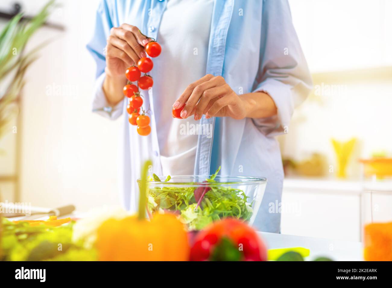 Die junge Frau in der heimischen Küche bereitet einen echten Salat mit frischem Gemüse zu Stockfoto
