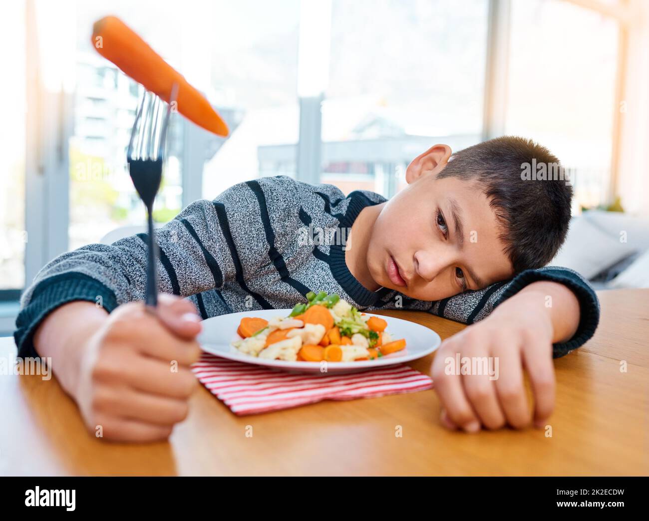 Ich glaube, ich habe jetzt meinen Appetit verloren. Aufnahme eines unglücklichen Jungen, der sich weigert, sein Gemüse zu Hause zu essen. Stockfoto