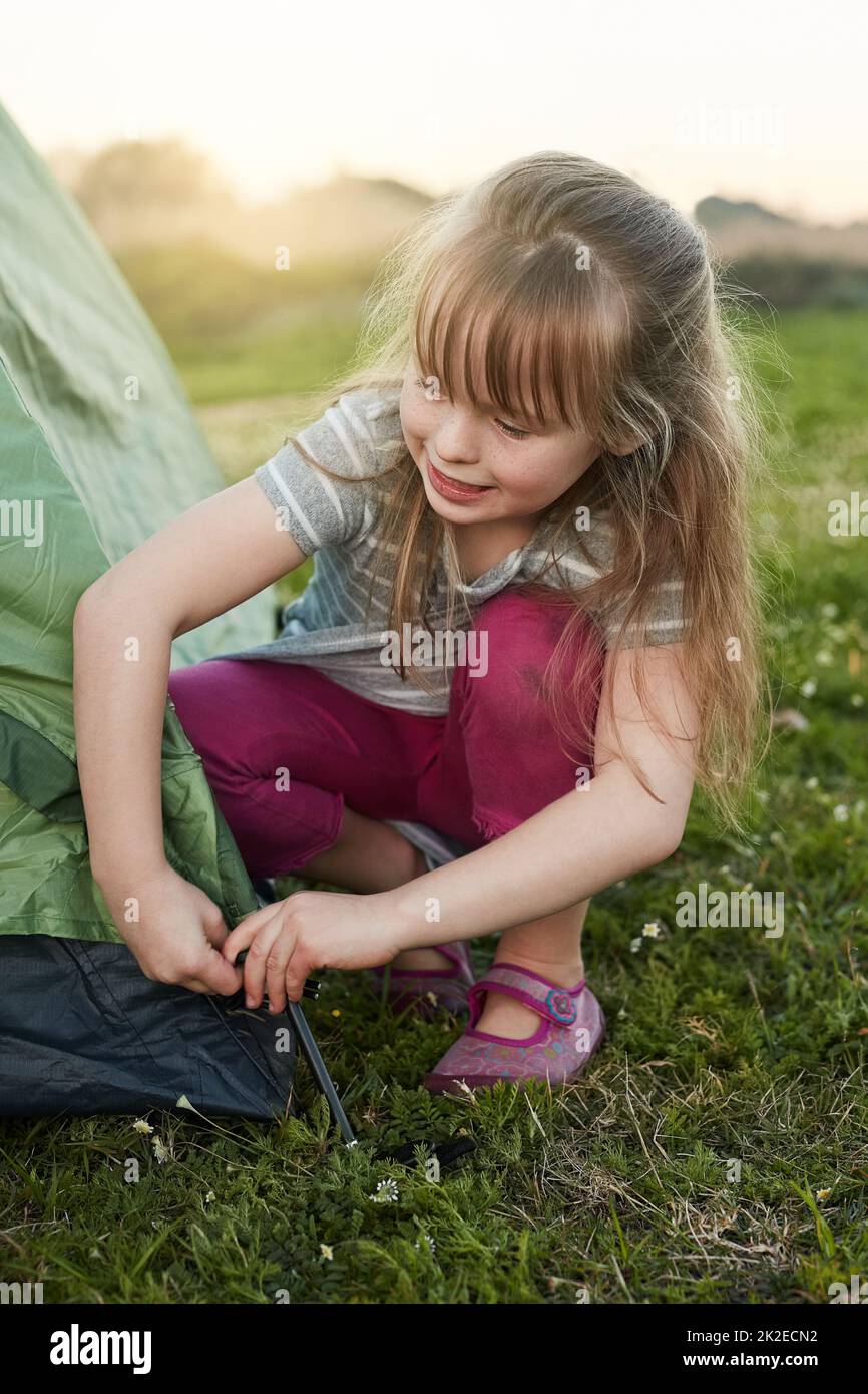 Rufen Sie mich einfach den Lagermeister an. Eine kurze Aufnahme eines kleinen Mädchens, das alleine ein Zelt aufstellt. Stockfoto