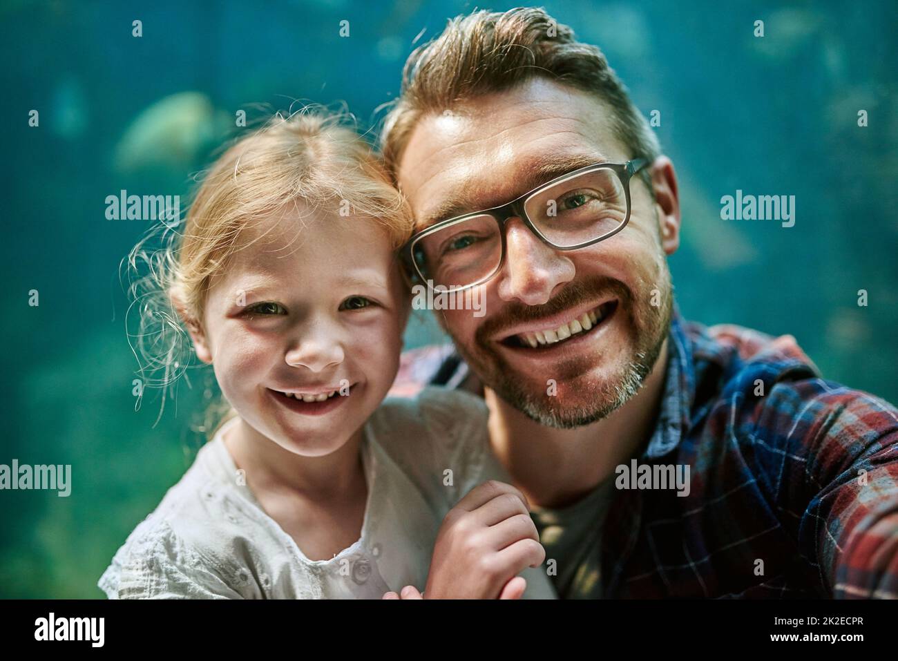 So bleibt das Erlebnis für immer bestehen. Porträt eines Vaters und seiner kleinen Tochter, die zusammen ein Selfie in einem Aquarium machen. Stockfoto