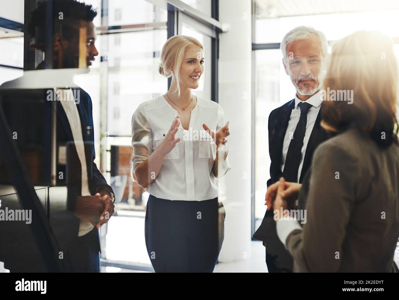 Shes hat eine tolle Idee. Eine kurze Aufnahme von vier Geschäftsleuten, die im Büro stehen und sprechen. Stockfoto