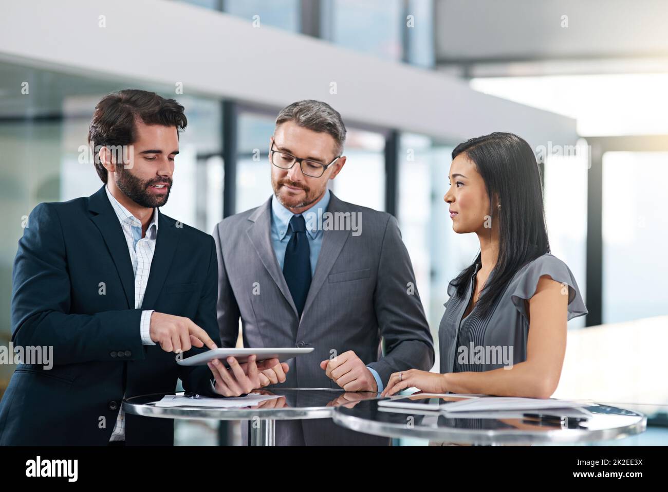 Lassen Sie sie einen Vorgeschmack bekommen. Eine kurze Aufnahme einer Gruppe von Geschäftsleuten, die im Büro über ein digitales Tablet schauten. Stockfoto