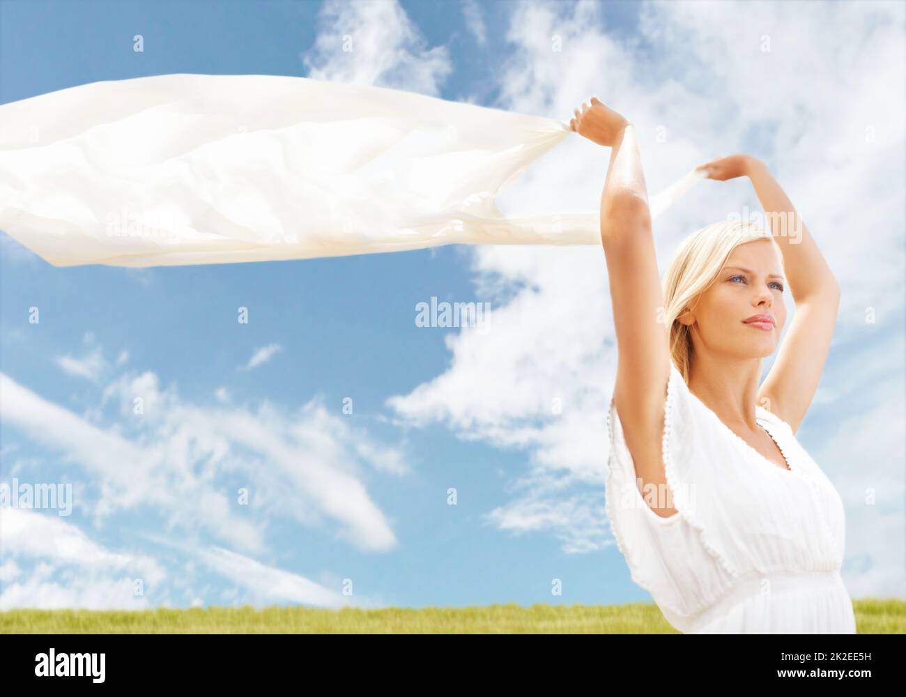 Freiheit im Wind finden. Eine schöne junge Frau, die einen Schal in der Brise hält. Stockfoto
