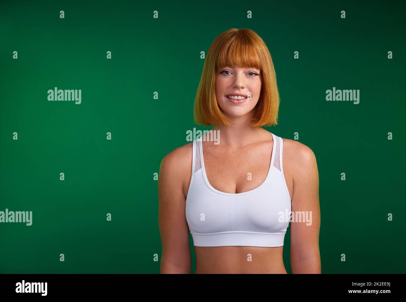 Verpflichten Sie sich, fit zu sein. Beschnittenes Porträt einer attraktiven jungen Sportlerin, die allein vor grünem Hintergrund im Studio steht. Stockfoto