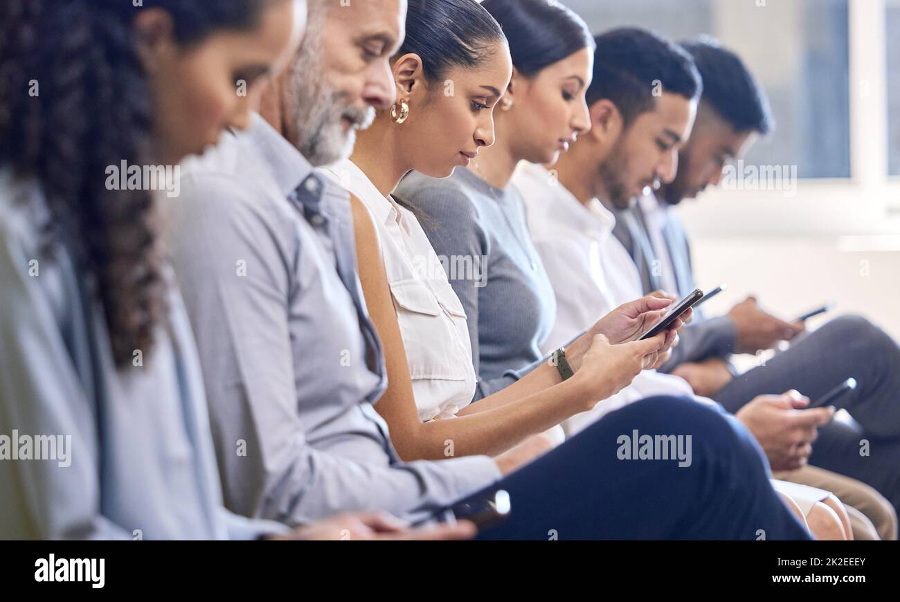 Es ist keine Ablenkung, sondern ein wichtiges Werkzeug. Freigestellte Aufnahme einer Gruppe von Geschäftsleuten, die während einer Konferenz im Büro ihre Handys benutzen. Stockfoto