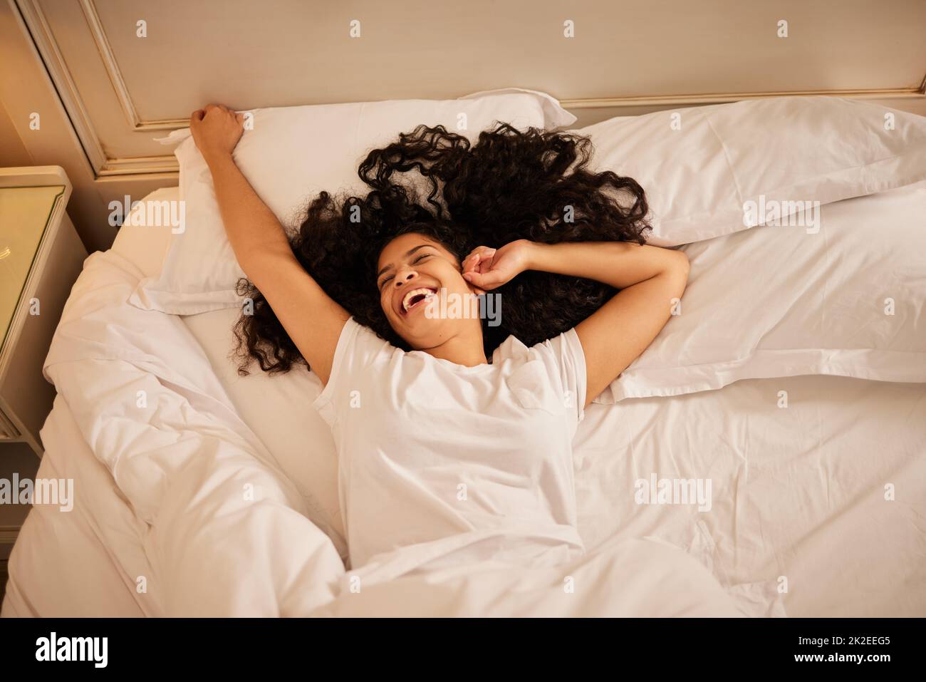 Eine gute Nachtruhe kann Wunder für Ihre Stimmung tun. Aufnahme einer jungen Frau, die sich zu Hause im Bett streckt. Stockfoto