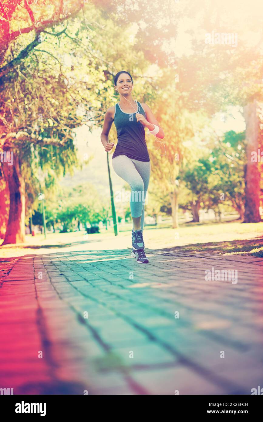 Sie läuft eine Meile von Fett. Aufnahme einer jungen Frau, die in einem Park trainiert. Stockfoto