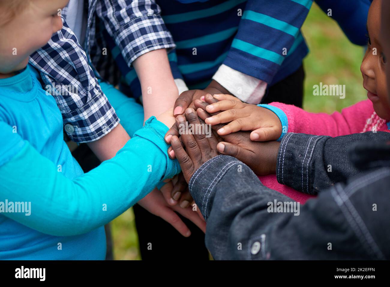 Freunde für immer. Aufnahme einer vielfältigen Gruppe von Kindern, die mit den Händen zusammen stehen. Stockfoto