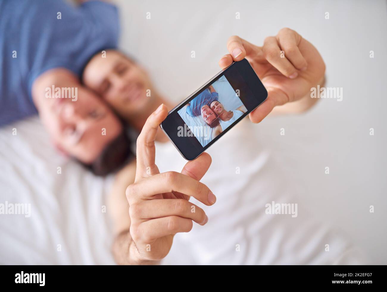 Einen Moment der Liebe festhalten. Aufnahme eines jungen schwulen Paares, das ein Selfie beim Entspannen im Bett gemacht hat. Stockfoto