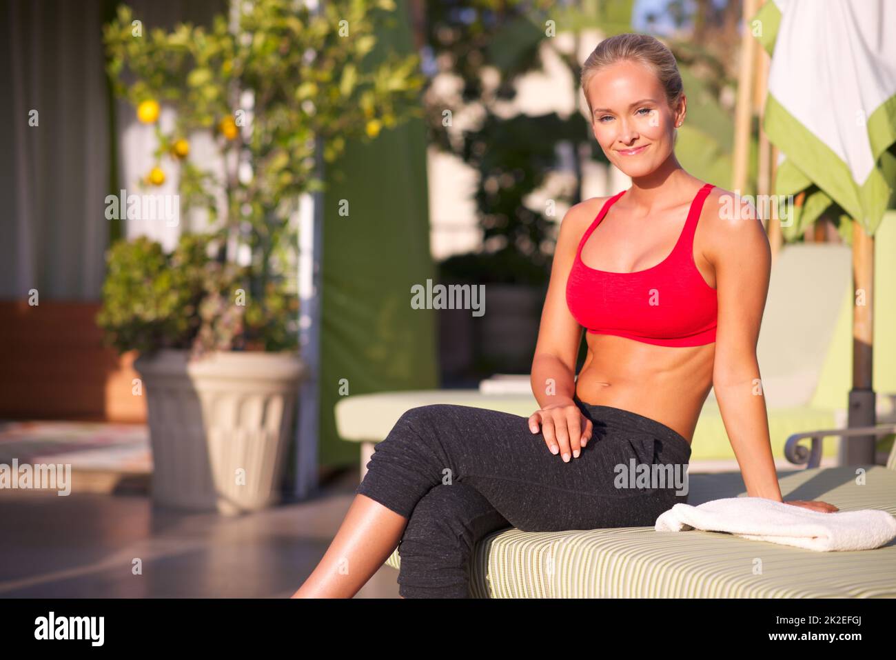 Fitness ist etwas, worüber man lächeln kann. Porträt einer attraktiven Frau in Sportkleidung, die draußen sitzt. Stockfoto