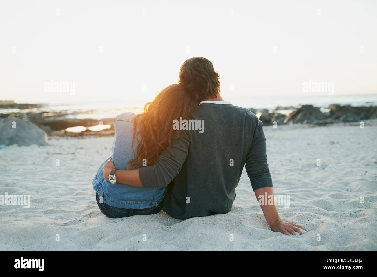 Diese besonderen Momente zu schätzen. Rückansicht eines liebevollen jungen Paares, das sich am Strand festklebete. Stockfoto