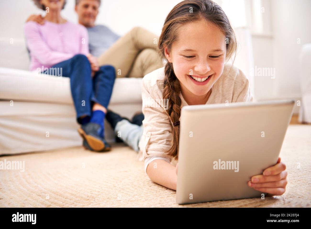Unterhalten bleiben, wo immer sie ist. Aufnahme von Großeltern, die ihre Enkelin mit einem digitalen Tablet beobachten. Stockfoto
