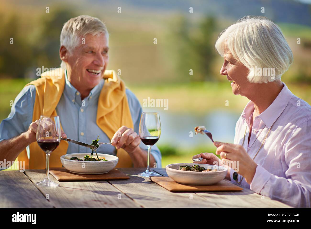 Noch in ihren älteren Jahren datierend. Ein kurzer Schuss eines älteren Ehepaares, das Wein trinkt, während er im Freien eine Mahlzeit genießt. Stockfoto