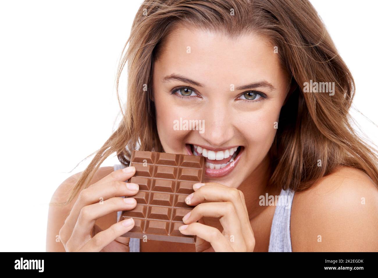 MMMM... sehr lecker. Eine attraktive junge Frau, die eine Schokoladenplatte isst. Stockfoto