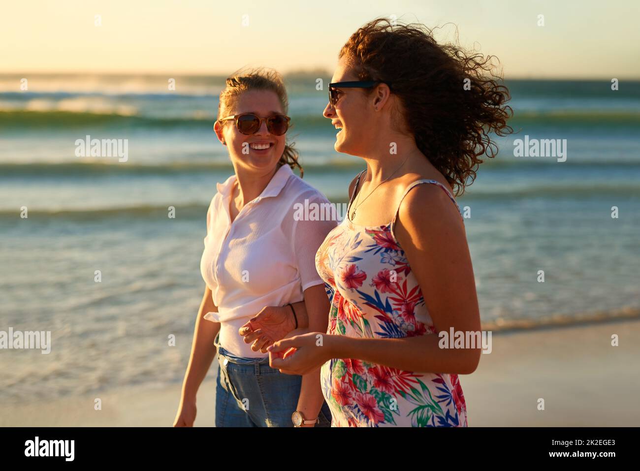 Wer einen Strandtag mit Bestie nicht mag. Eine kurze Aufnahme von zwei attraktiven jungen Freundinnen, die sich beim Strandspaziergang unterhalten. Stockfoto