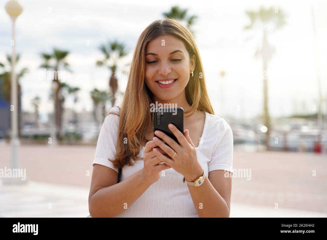 Tourist Mädchen auf der Suche nach Hotel auf Handy. Reisende Frau, die ein Zimmer für die Nacht über ein Mobiltelefon gebucht hat. Last-Minute-Reisekonzept. Stockfoto