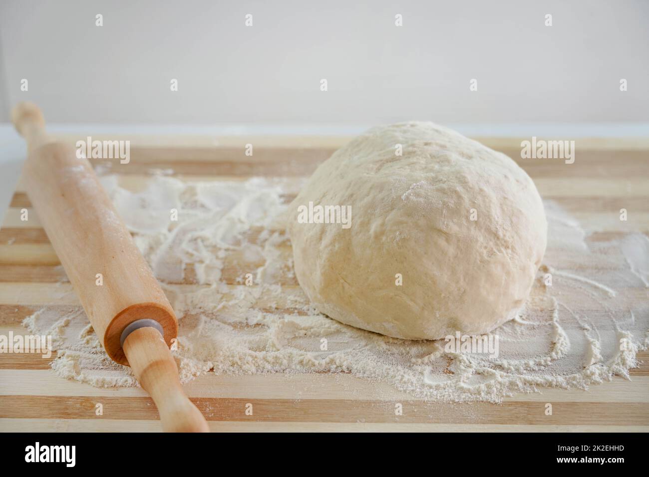 Nahaufnahme von Nudelholz und Teig auf Holztisch mit Mehl. Grundbedürfnisse und Preissteigerungen Konzept. Stockfoto