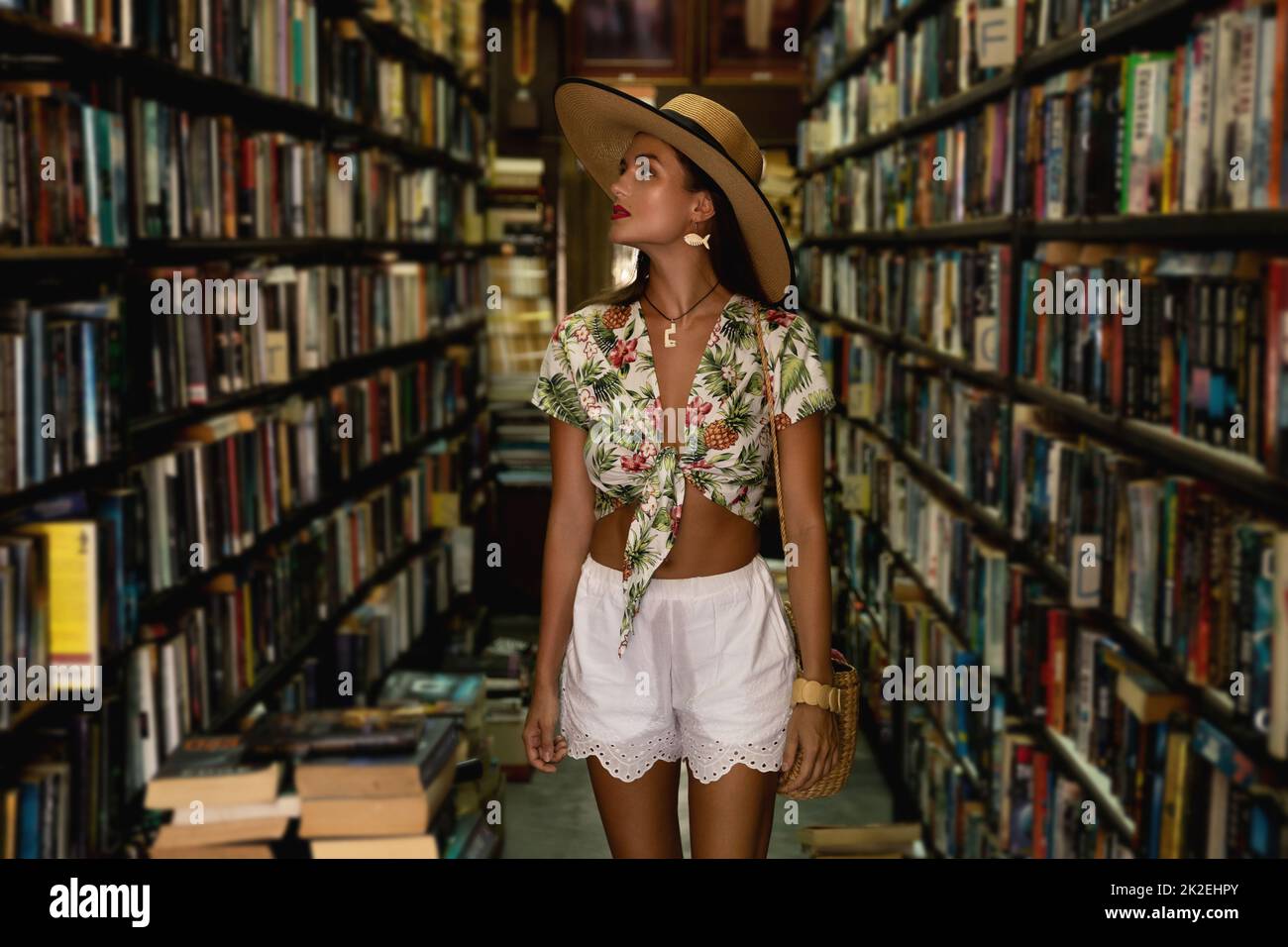 Schönes Mädchen trägt stilvolles Outfit auf der Suche nach interessanten Buch in der Vintage-Buchhandlung Stockfoto