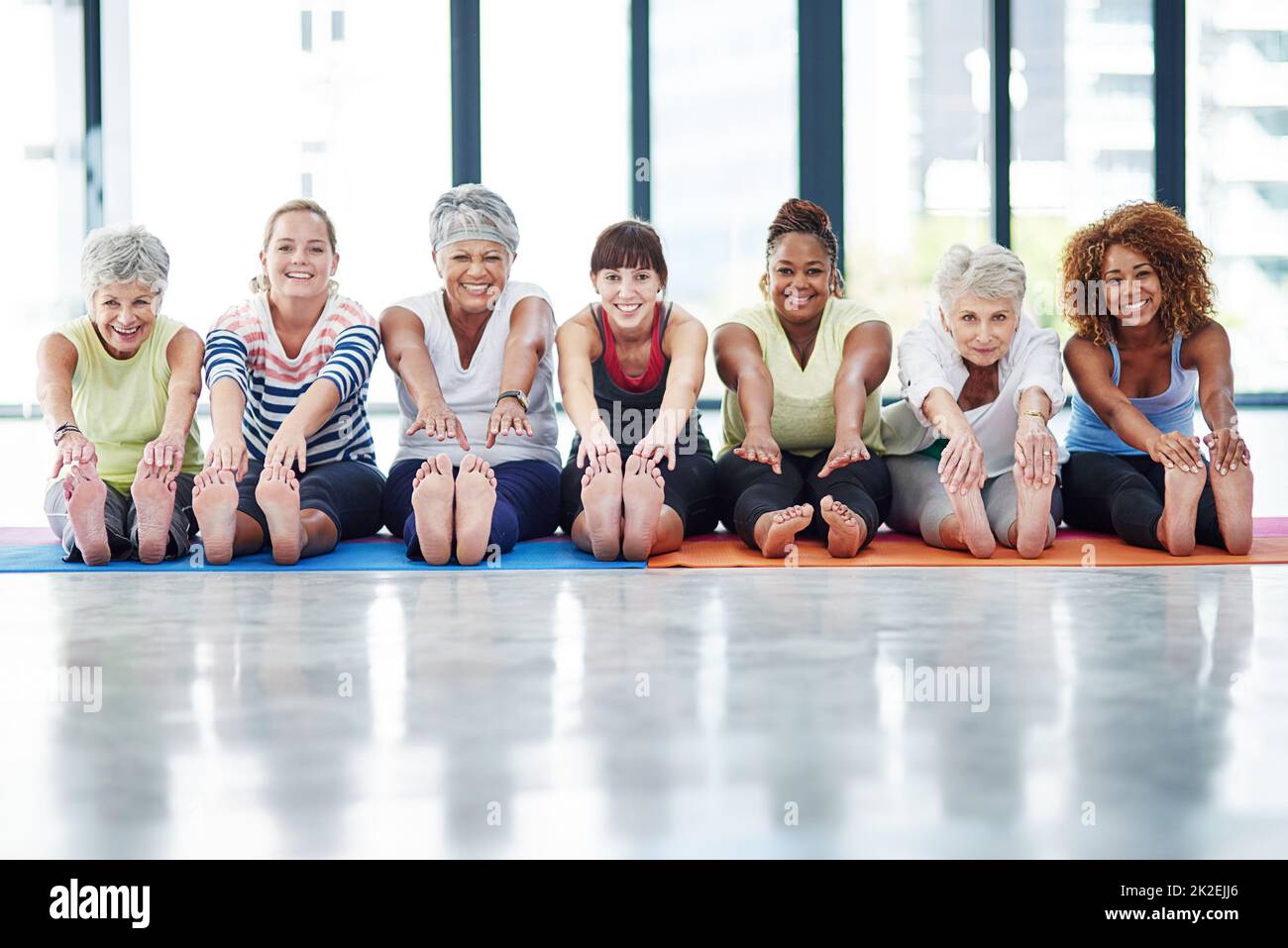 Gruppenübung ist die beste Übung. Aufnahme einer Gruppe von Frauen, die sich in Innenräumen aufwärmen. Stockfoto