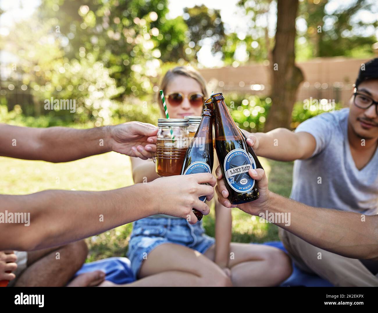 Prost zum Leben. Eine kleine Aufnahme einer jungen Gruppe von Freunden, die in der Sommersonne ein paar Drinks genießen und dabei toasten. Stockfoto