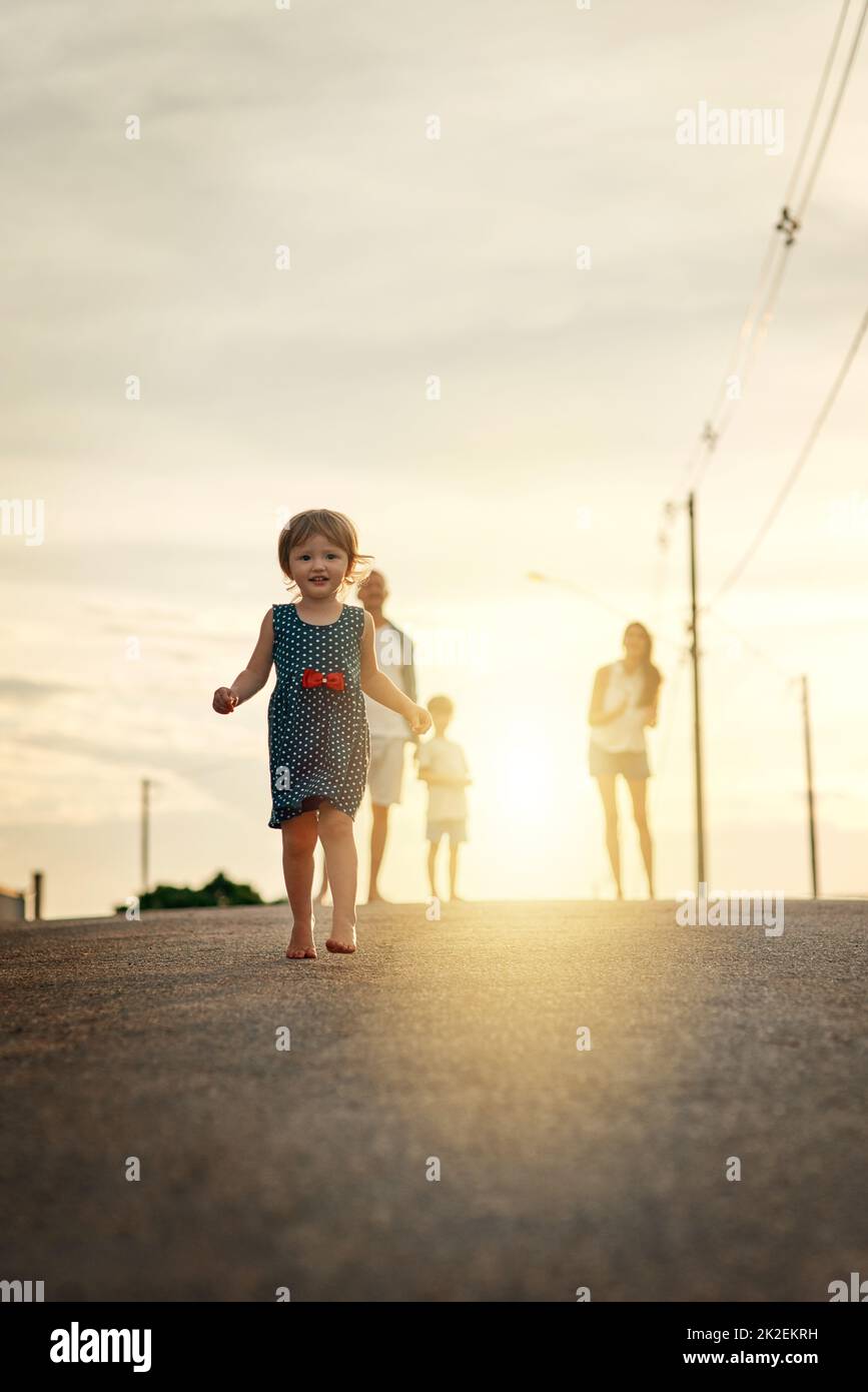 Sie liebt es, die Straße hinunter zu laufen. Aufnahme einer jungen Familie, die in der Nachbarschaft zusammenläuft. Stockfoto