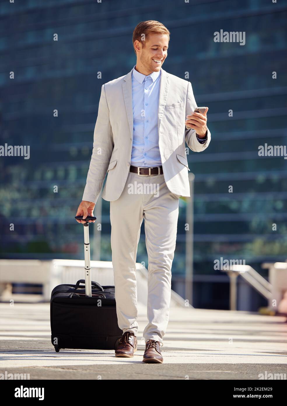 Harte Arbeit bringt Sie an die Plätze. Aufnahme eines jungen Geschäftsmannes, der ein Mobiltelefon benutzt, während er mit einem Koffer in der Stadt spazierenging. Stockfoto