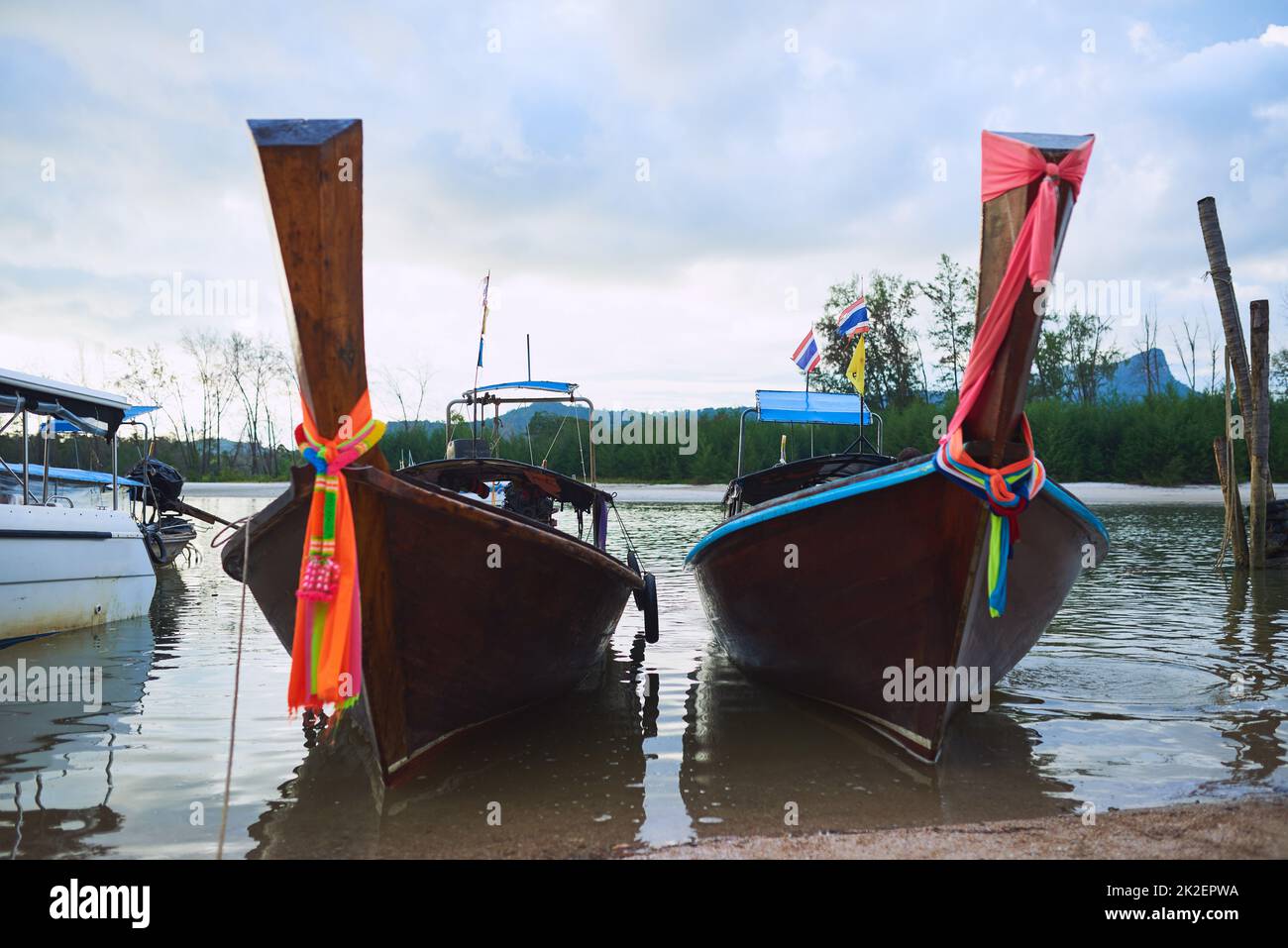 Bereit für ein Abenteuer. Aufnahme von traditionellen Holzbooten, die an einem Strand in Thailand ruhen. Stockfoto