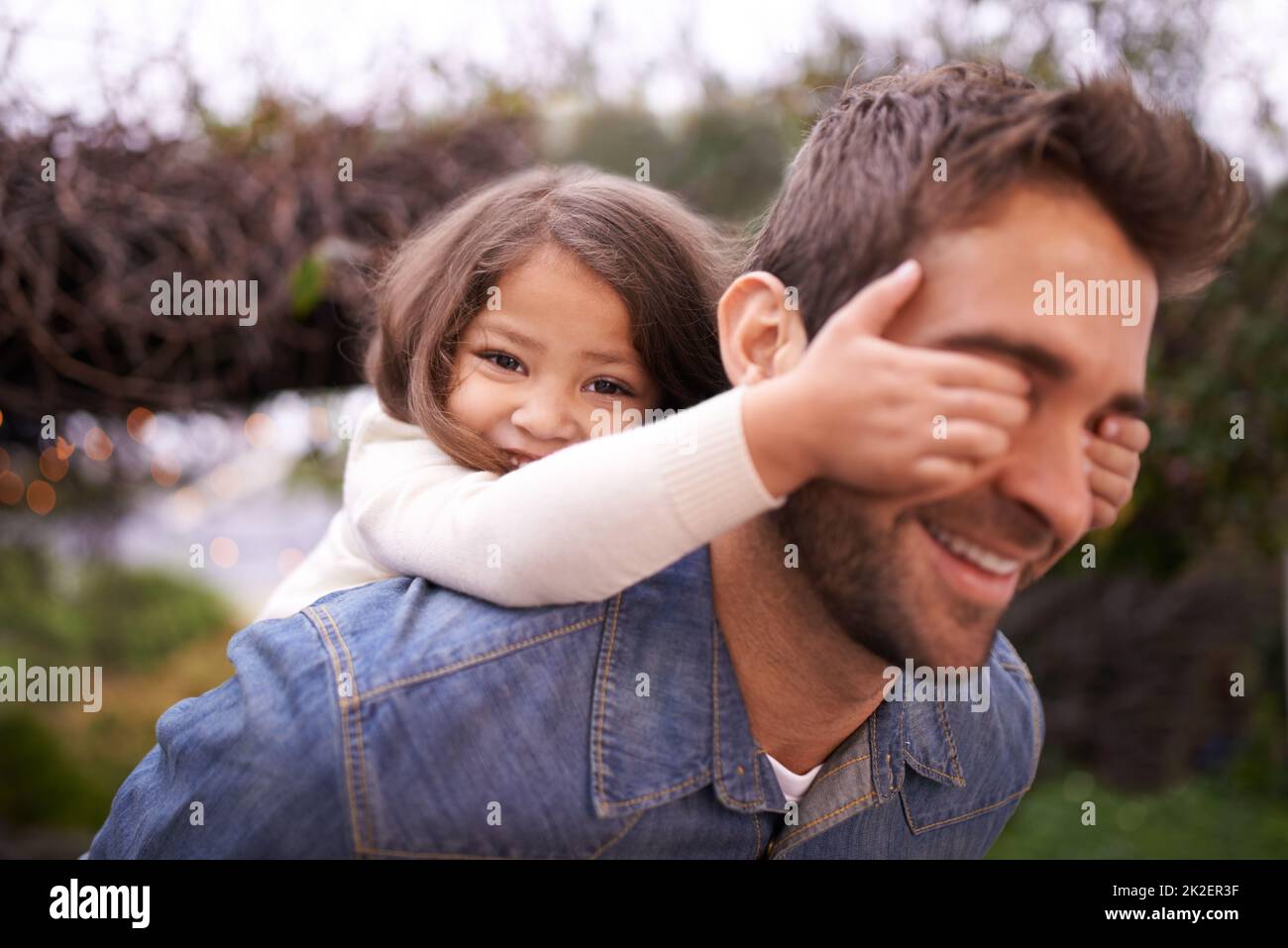 Raten Sie mal, wer. Ein kleines Mädchen und ihr Vater spielen draußen. Stockfoto