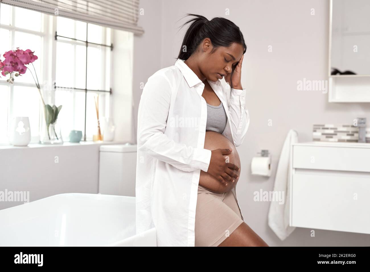 Sich durch die Herausforderungen der Schwangerschaft zu kämpfen. Aufnahme einer Schwangeren, die zu Hause unwohl aussieht. Stockfoto