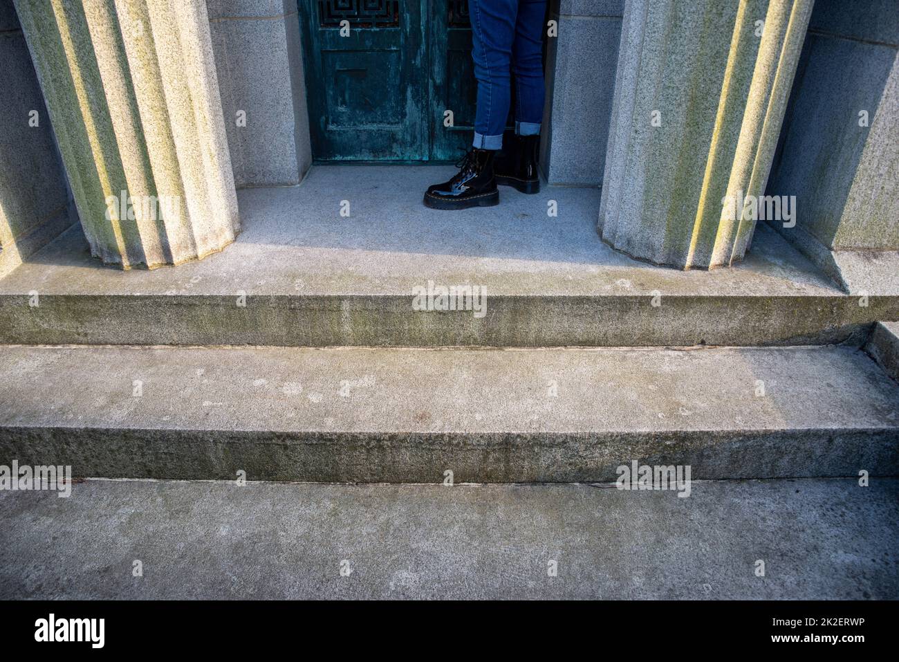 Eine Person steht allein durch die Türen eines Mausoleums mit Säulen Stockfoto
