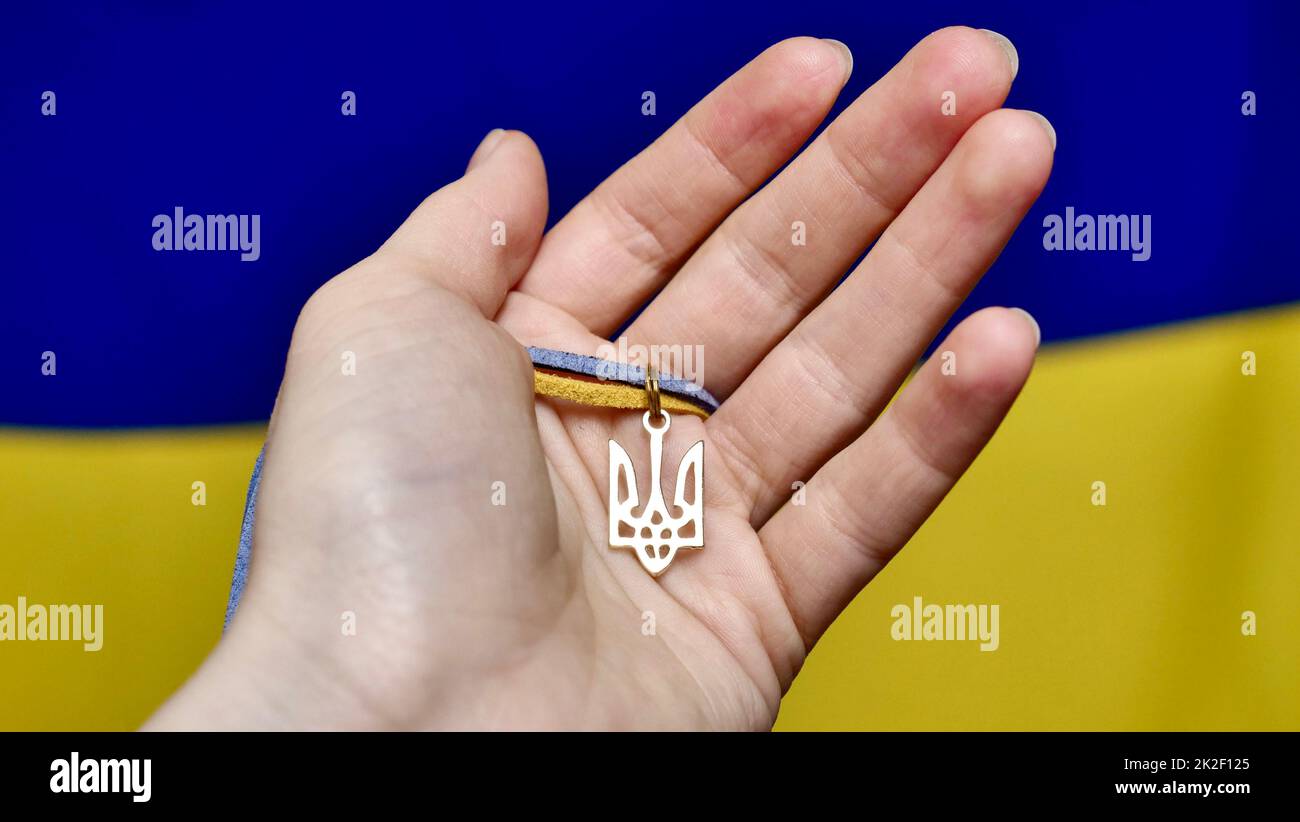 Ukrainisches Staatslogo in der Hand der Flagge Stockfoto