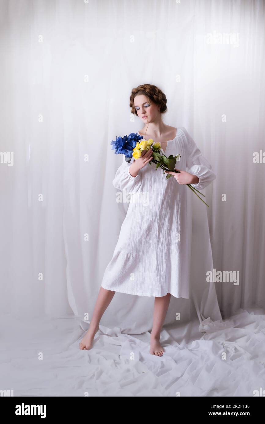 Ukrainisches Mädchen mit blau gelben Blüten in weiß Stockfoto
