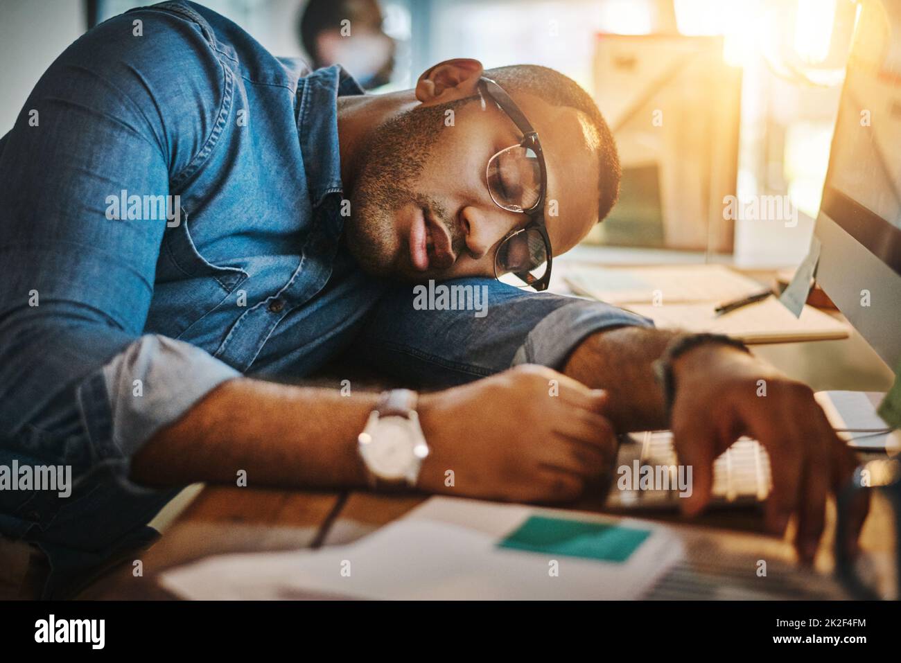 HES hat den Punkt der Produktivität überschritten. Aufnahme eines erschöpften jungen Geschäftsmannes, der in einem modernen Büro an seinem Schreibtisch schläft. Stockfoto