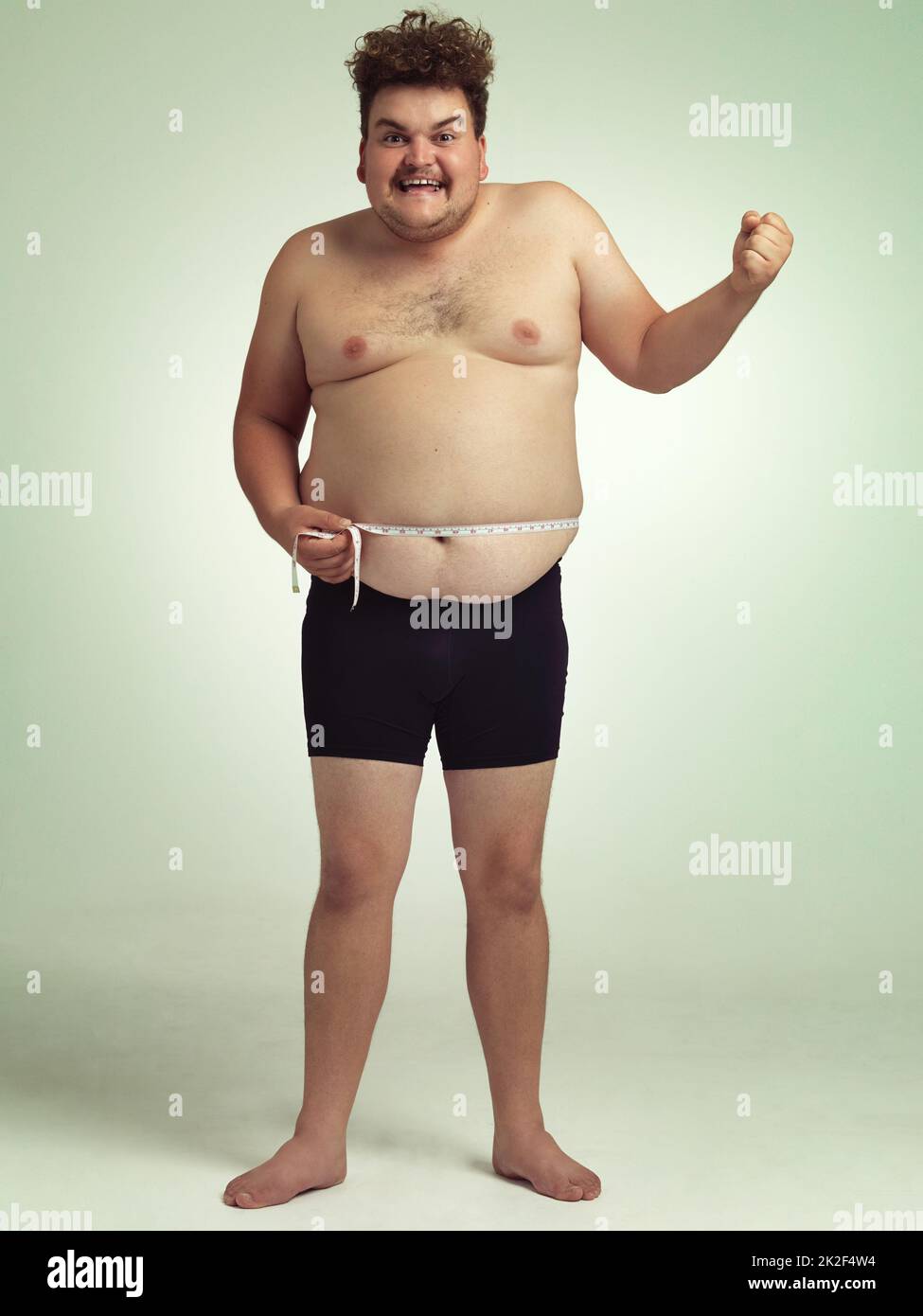 Abnehmen und sich großartig fühlen. Aufnahme eines übergewichtigen Mannes, der sich selbst misst. Stockfoto