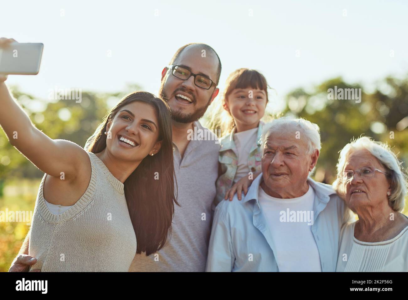 Im Leben geht es darum, diese glücklichen Momente zu sammeln. Aufnahme einer glücklichen Familie, die zusammen ein Selfie im Park macht. Stockfoto